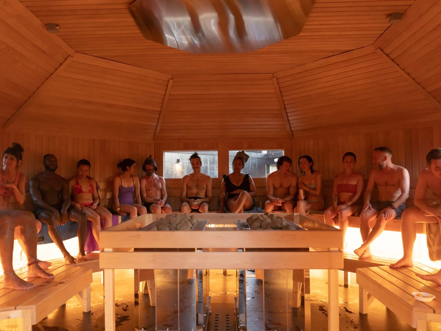 People sitting together around the stove inside the Community Sauna Baths sauna